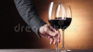 豪华红酒。 手拿着一个酒杯，在棕色背景下从桌子上拿出美味的葡萄酒。 玫瑰酒